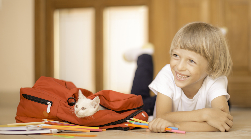 Child packing a school backpack, representing back-to-school pet routine adjustment tips